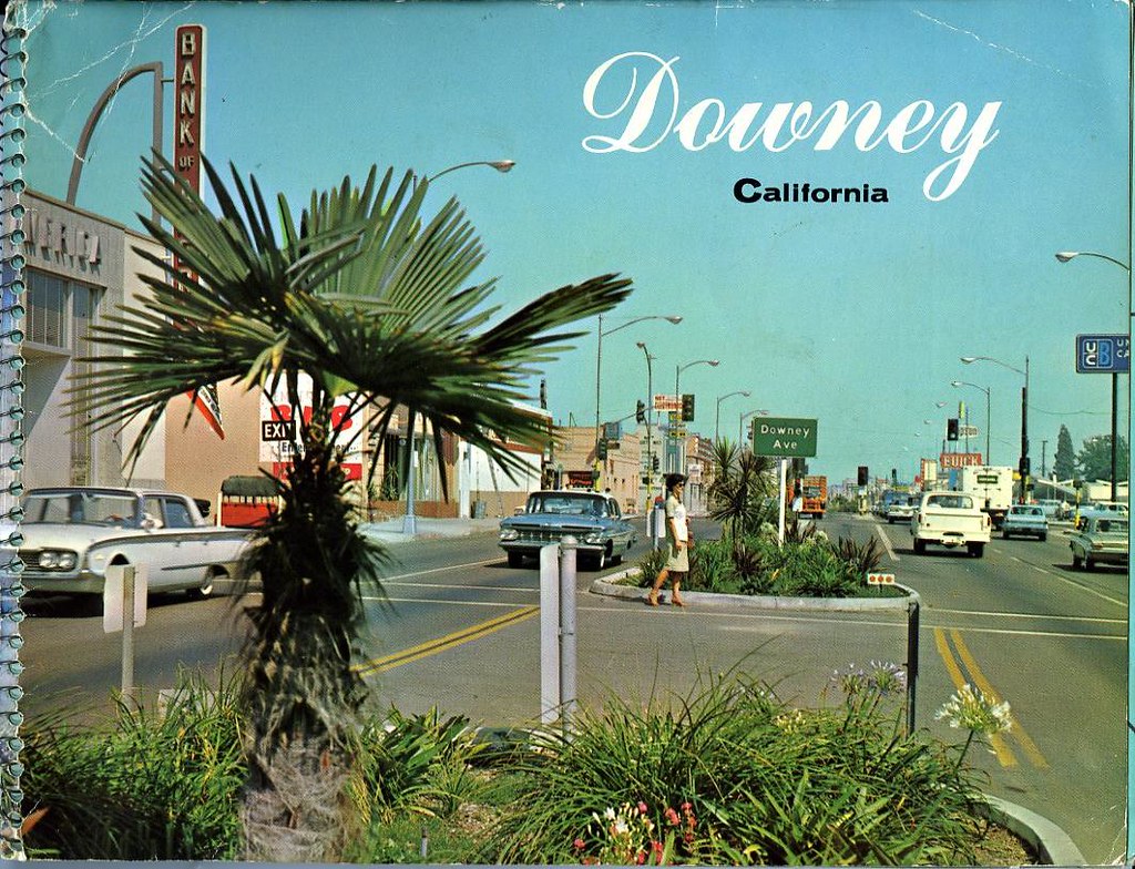 Mid-century view of Downey Avenue with cars, storefronts and palm trees