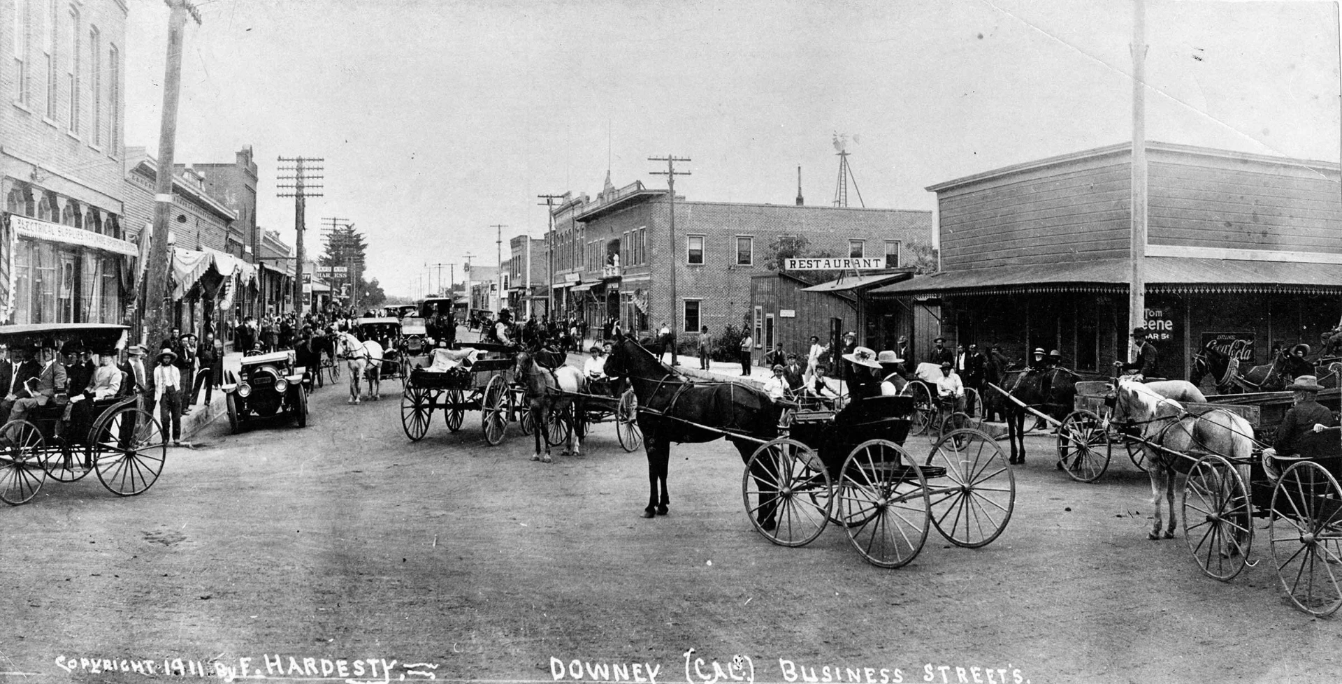 Downey business streets crowded with horse-drawn carriages and early automobiles in 1911